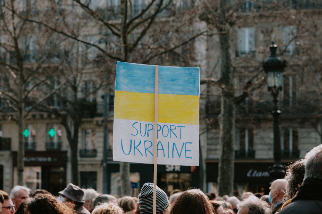 gallery-4 Crowd holding a 'Support Ukraine' banner during an outdoor solidarity rally.